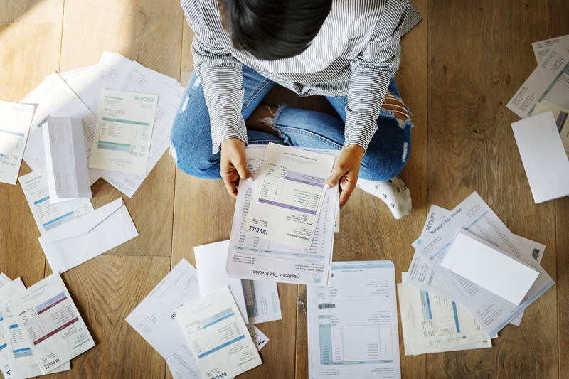 Photo of a woman sitting on the floor with bills spread out